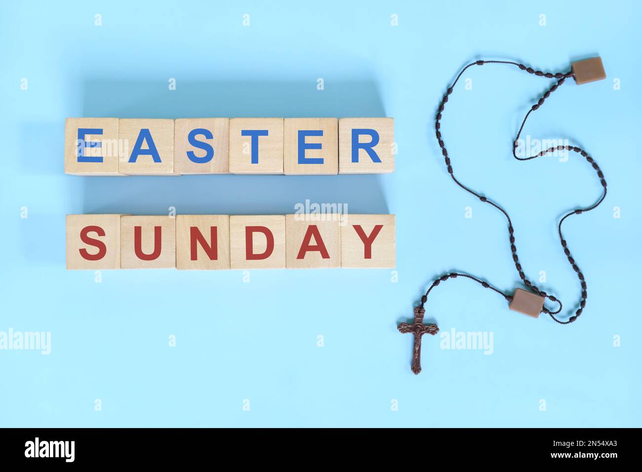 Ostersonntag - Konzept der Heiligen Woche. Holzblocktypographie mit Rosenkranz auf blauem Hintergrund. Stockfoto