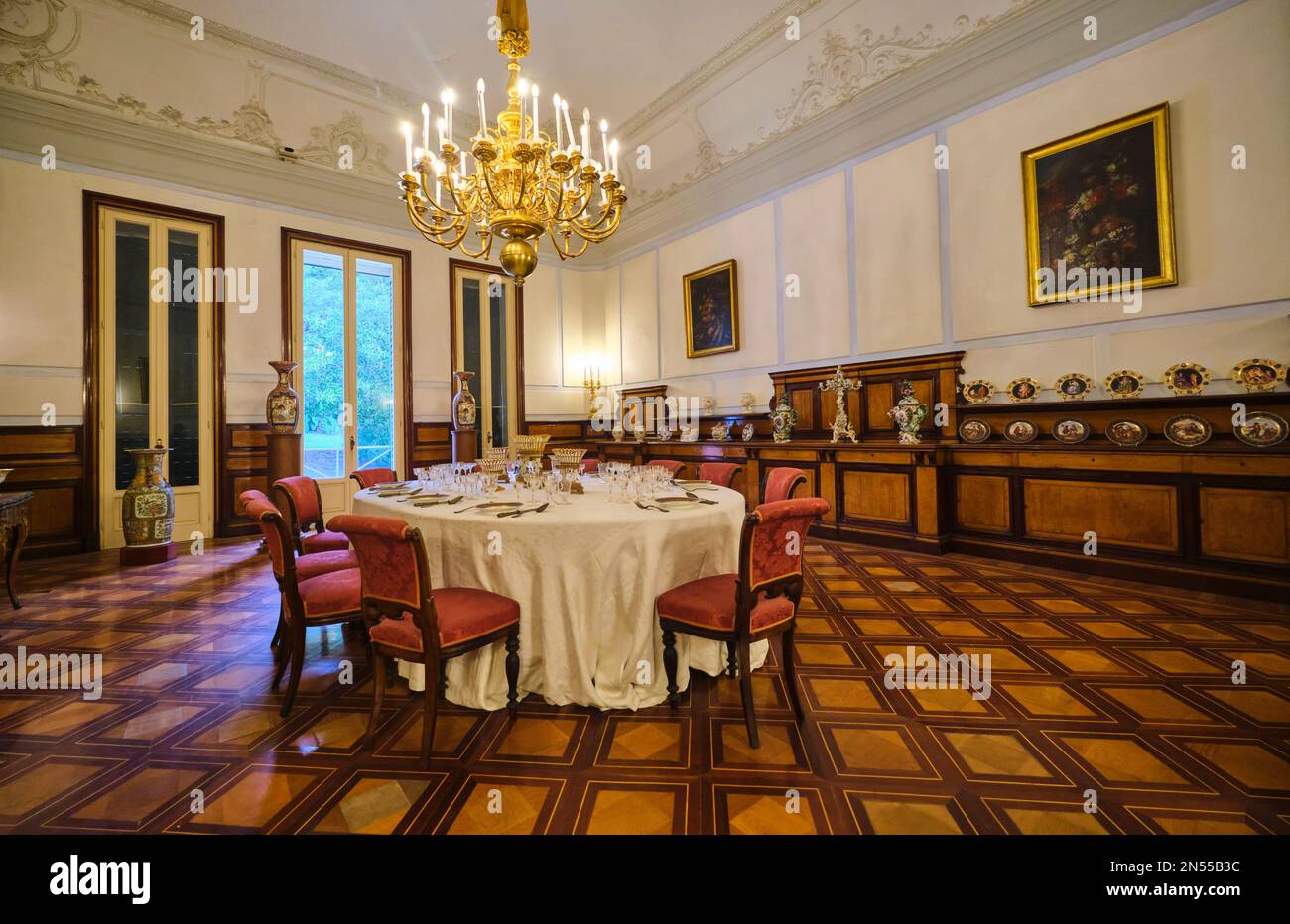 Großer Speisesaal mit ovalem Tisch und Holzeinlegeböden. Im Herrenmuseum, Museo Pignatelli in Neapel, Neapel, Italien, Italien. Stockfoto