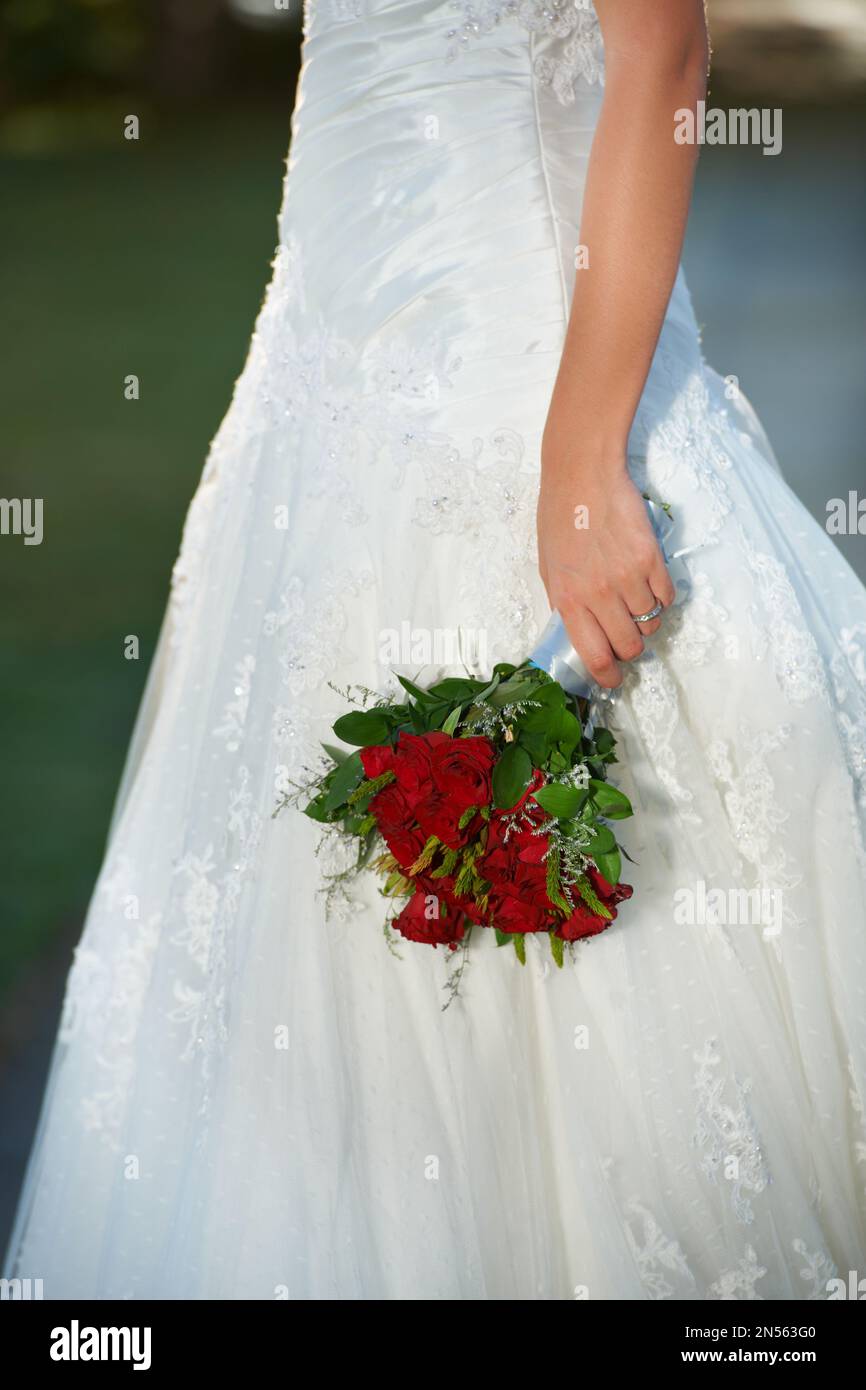 Bereit für den Sprung. Eine Braut mit einem Strauß roter Rosen. Stockfoto