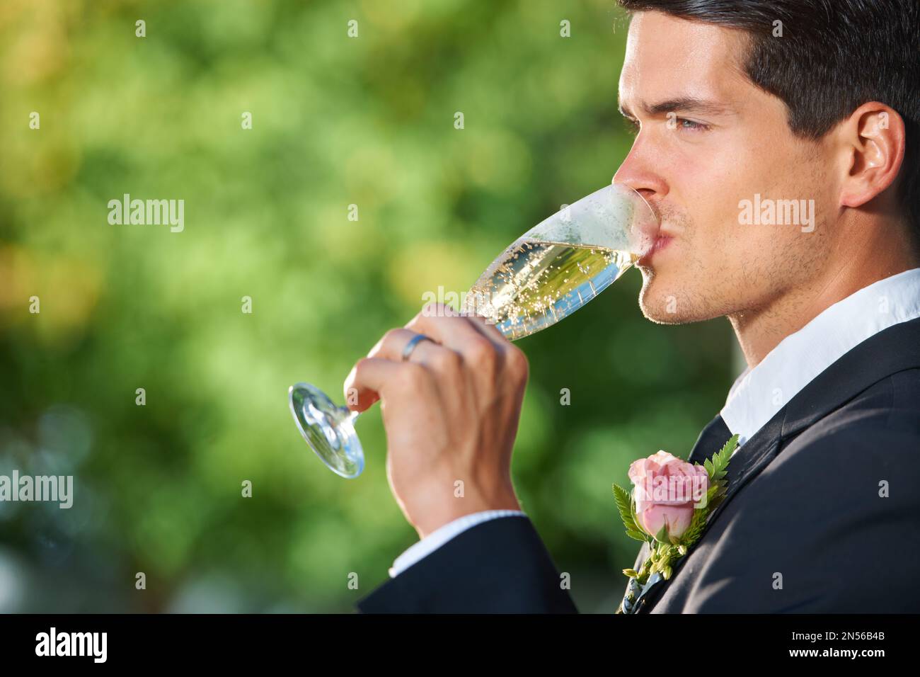 Genießen Sie einen ruhigen Drink an der Rezeption. Profilfoto eines jungen Bräutigams, der ein Glas Champagner trinkt. Stockfoto