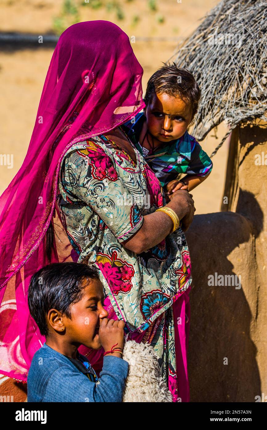 Farbenfroh gekleidete Wüstenbewohner, Schlammhütten in der Thar Wüste, Thar Wüste, Rajasthan, Indien Stockfoto