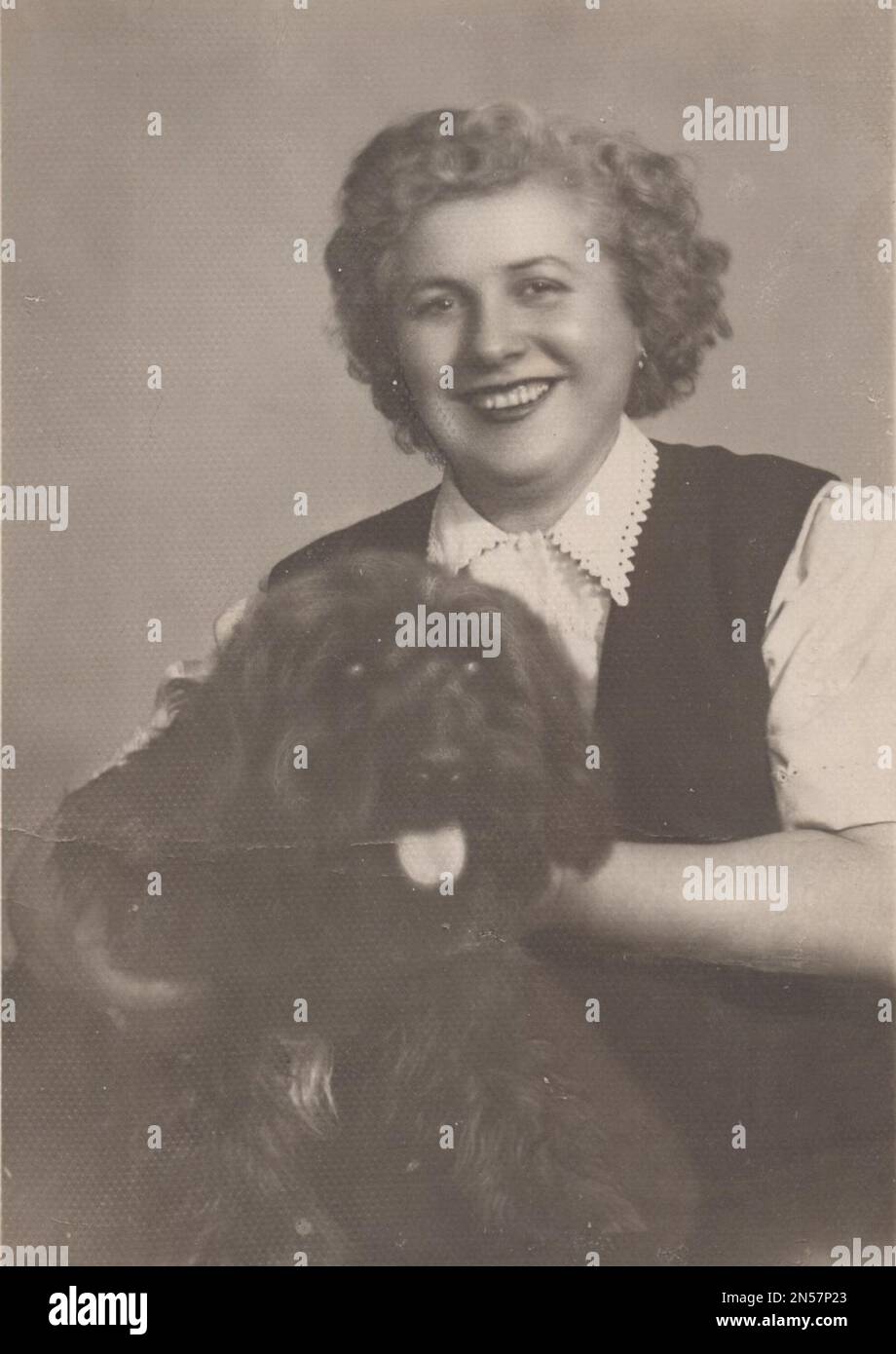 Vintage-Foto von Lady und ihrem Hund / Hündchen in der Hand / umarmende Hunde , Hundekugeln / Vintage-Lachen / lächelnde Dame / glückliche Frau / Hund unter den Armen halten Stockfoto
