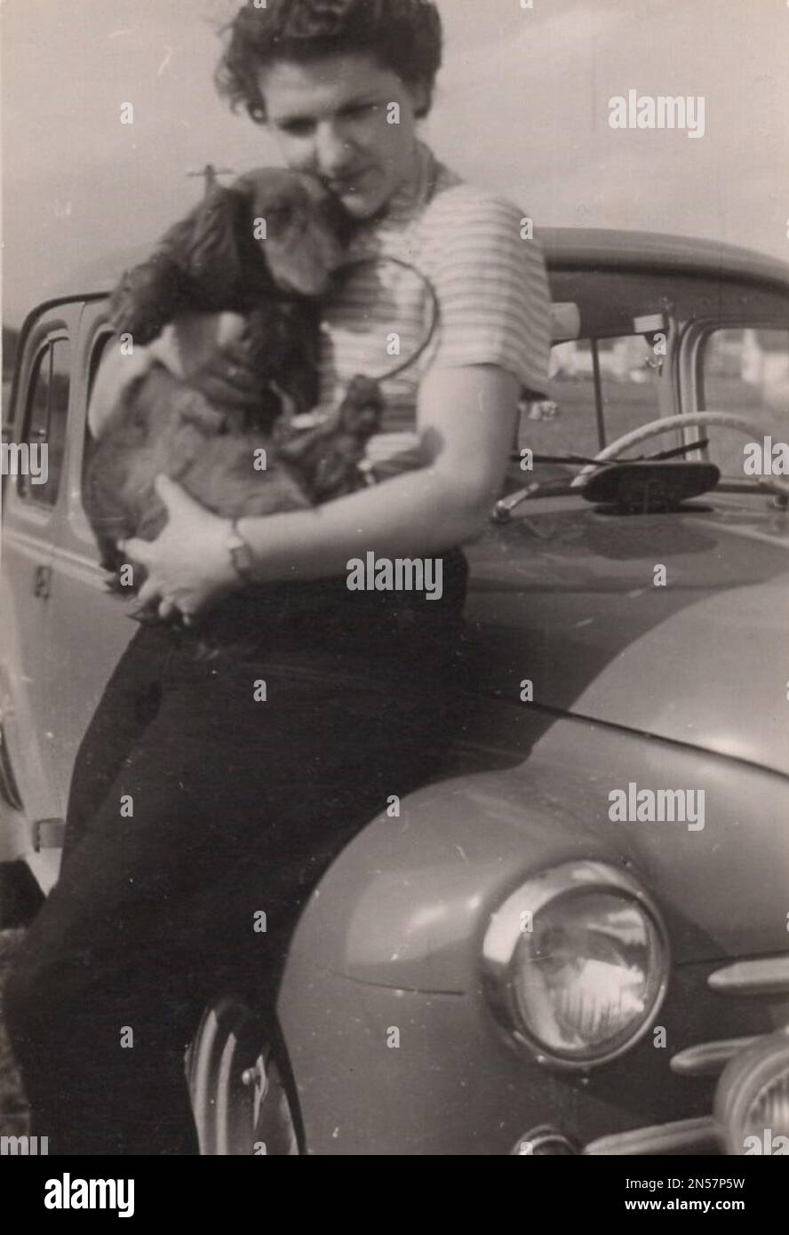 Vintage-Foto von Lady und ihrem Hund / Hündchen in der Hand / süßer Dachshund , alter Dachshund / umarmende Hunde , Hundehugs / Oldtimer / Fahrzeug / Dachshund-Liebhaber / Hund unter den Armen halten Stockfoto