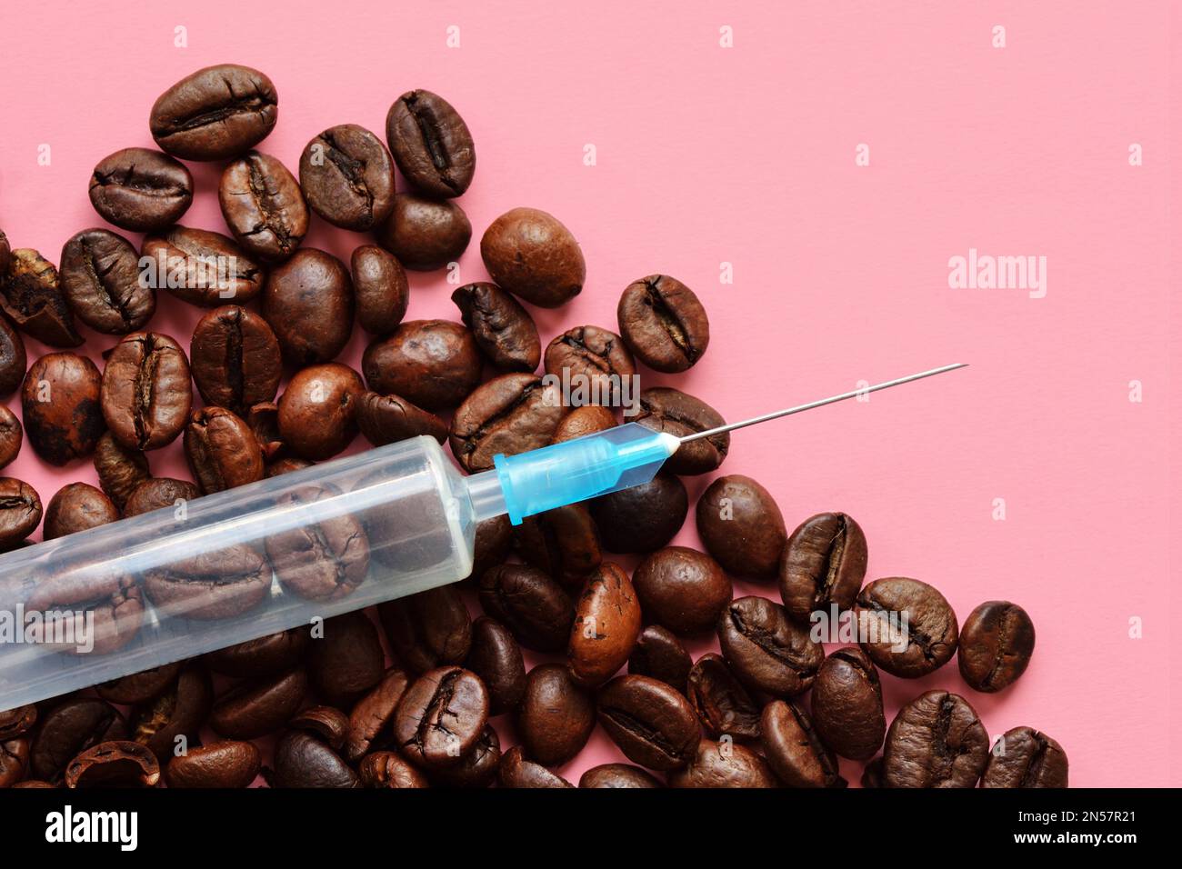 Spritze mit Kaffeebohnen auf rosa Hintergrund - Konzept von Kaffee und Gesundheit Stockfoto