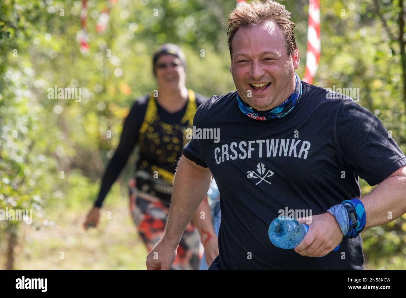 Ein lächelnder Läufer, der versucht, einen Angriffskurs zu absolvieren, flieht vor einem gejagten Zombie Stockfoto