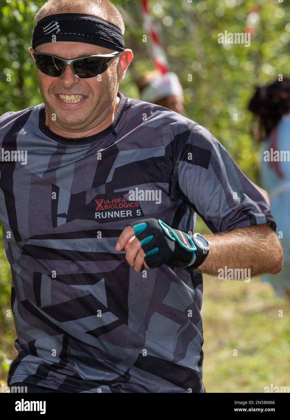 Ein lächelnder Läufer, der versucht, einen Angriffskurs zu absolvieren, flieht vor einem gejagten Zombie Stockfoto