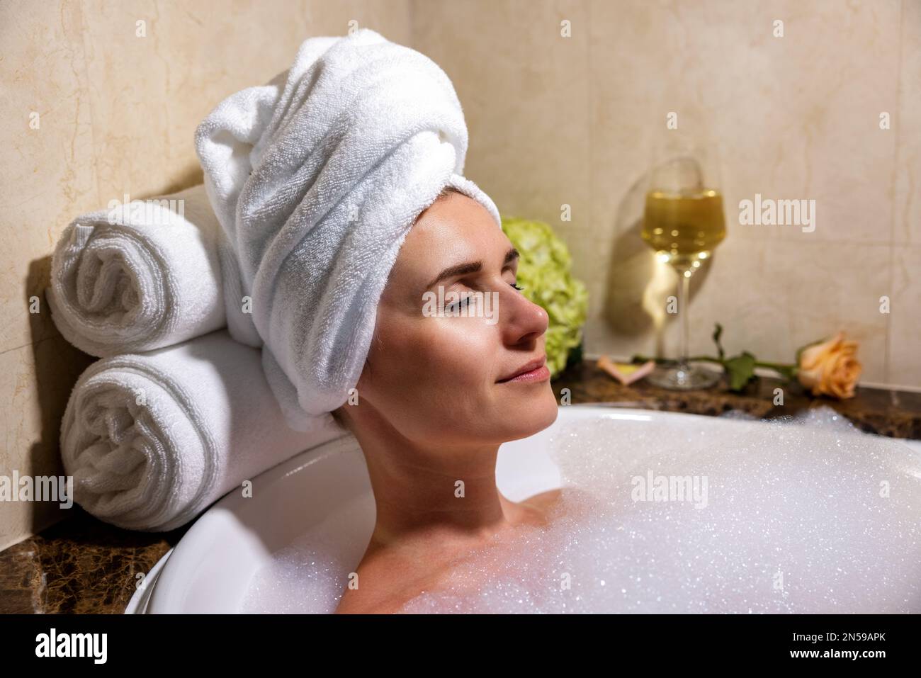 Eine Frau, die sich im Bad voller Schaum im SPA-Hotel erholte Stockfoto