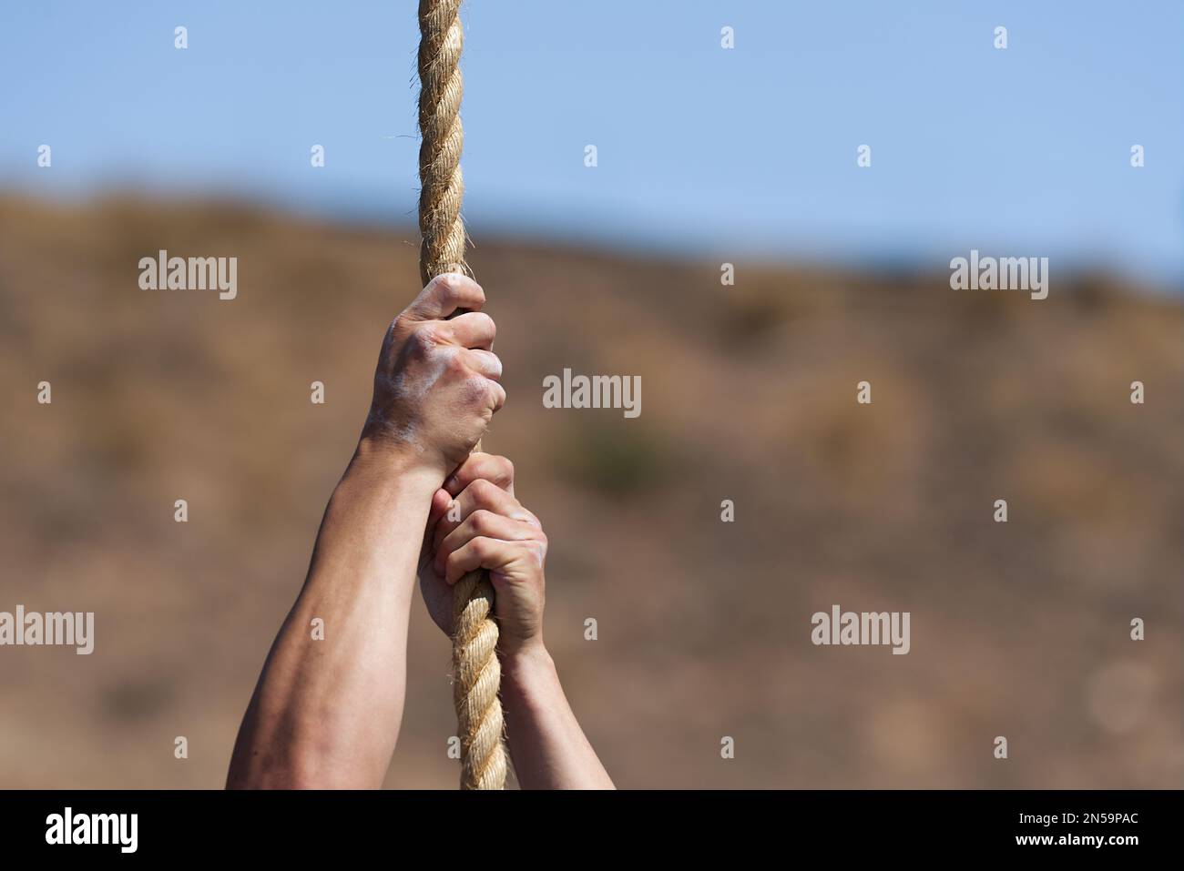 Sportlicher Mann, der trainiert und ein Seil hochklettert, während des Hinderniskurses im Boot Camp Stockfoto