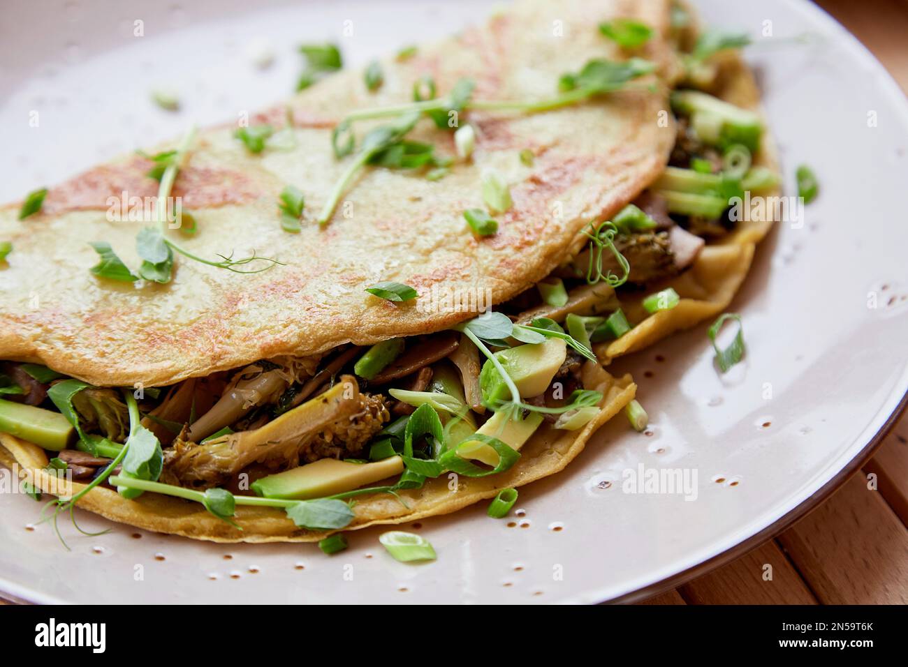 Nahaufnahme alternativer veganer Pfannkuchen gefüllt mit Pilzen, Erbsensprossen, Avocado. Gesundes Frühstück. Stockfoto