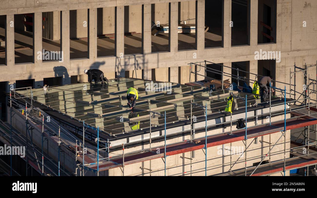 Dachdecker, der Fenster auf dem Dach eines Geschäftsgebäudes für einen Lichtschacht installiert. Stockfoto