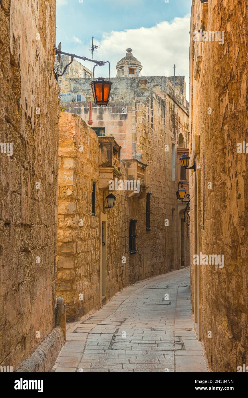 Alte mittelalterliche, enge Straße mit Straßenlaternen in Mdina, Malta mit niemandem. Vertikale Ausrichtung. Reiseziel Stockfoto