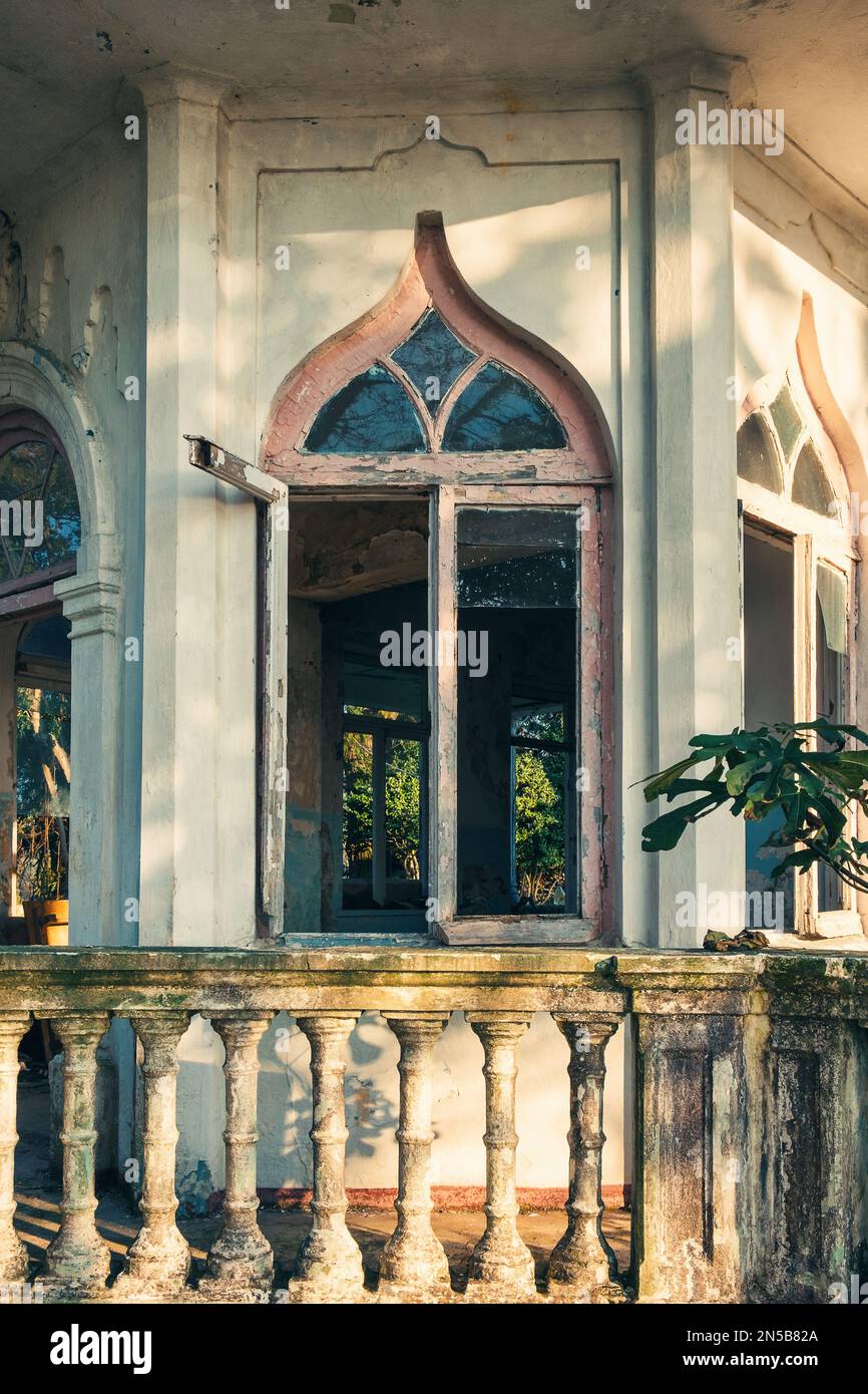 Altes Bogenfenster in einem verlassenen Haus oder Herrenhaus mit Terrasse. Vertikale Ausrichtung Stockfoto
