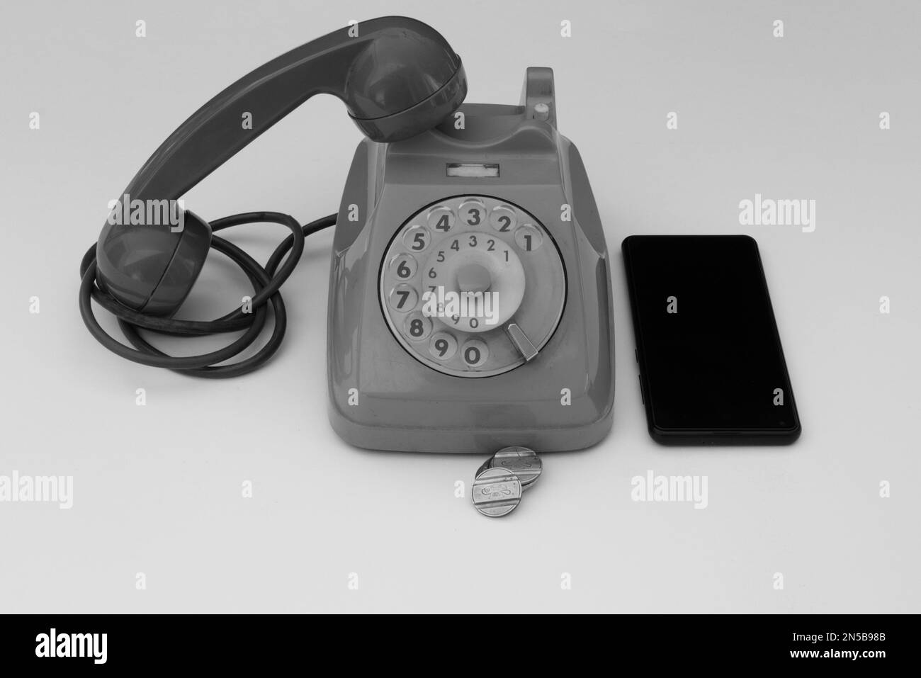 Bild eines alten Drehtelefons und eines Smartphones daneben. Die Entwicklung der Telefonie im Vergleich von Alt und Neu. Stockfoto