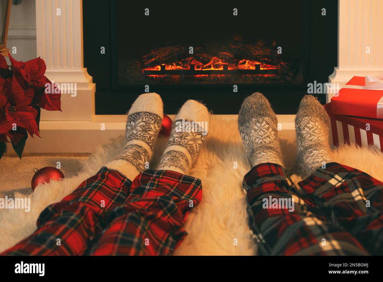 Ein Paar in warmen Socken ruht sich zu Hause am Kamin aus, schließt Stockfoto