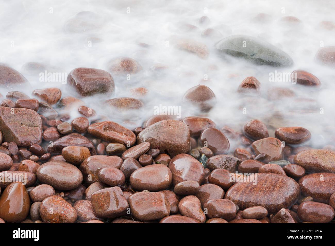 Wellen an einem Strand aus rotem Stein an der Nordwestküste Schottlands, Großbritannien, Schottland Stockfoto