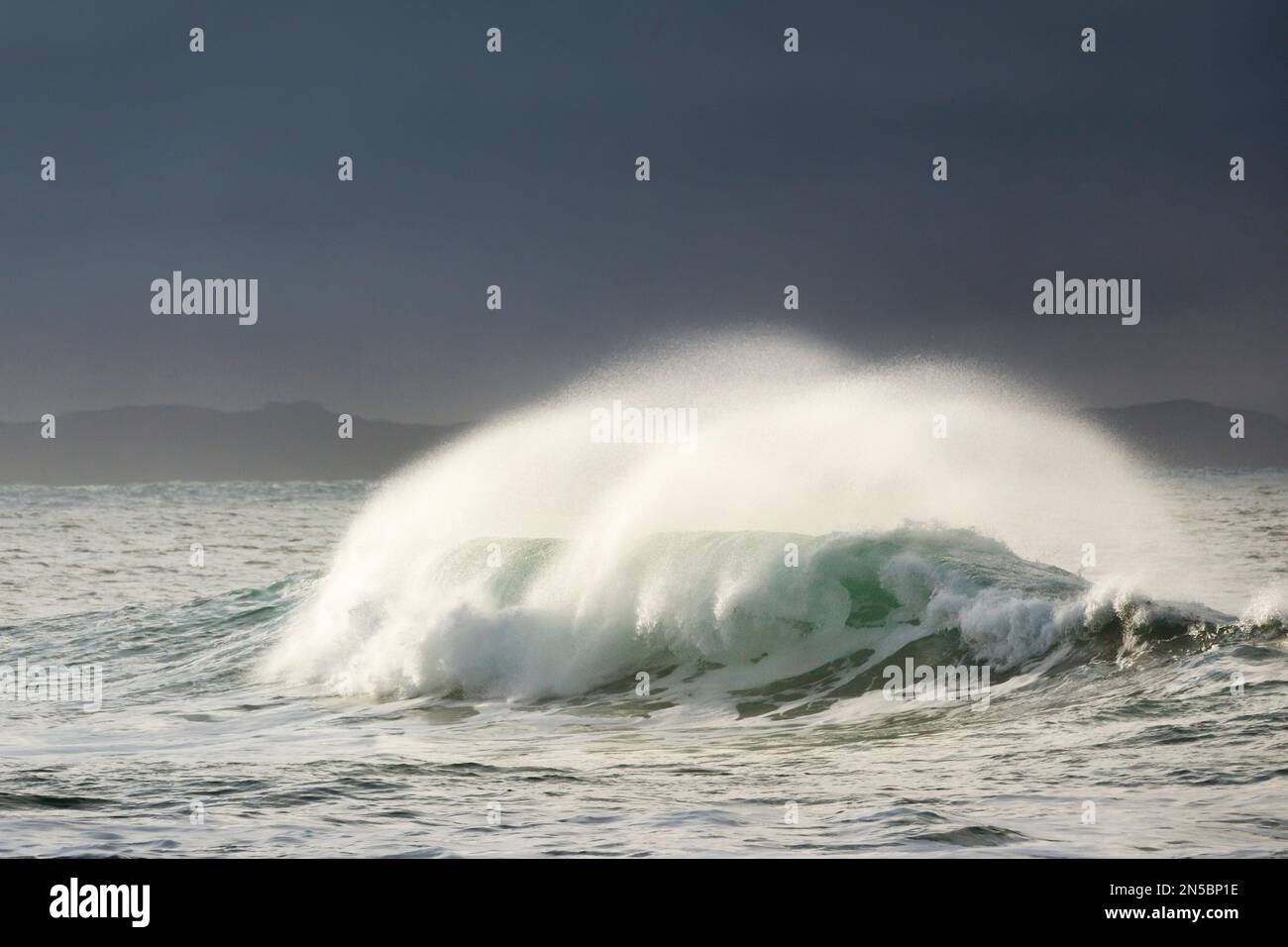 Große Welle bricht im Wintersturm auf offener See und dramatisches Licht vor der Nordküste Irlands, Irlands, Grafschaft Donegal, Fintra Beach Stockfoto