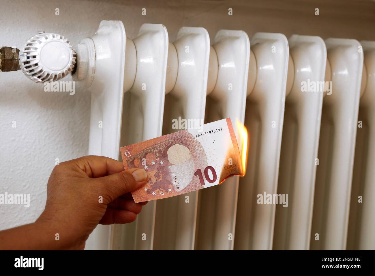 Hand mit brennender 10 Euro-Rechnung, Preiserhöhung für Heizung Stockfoto