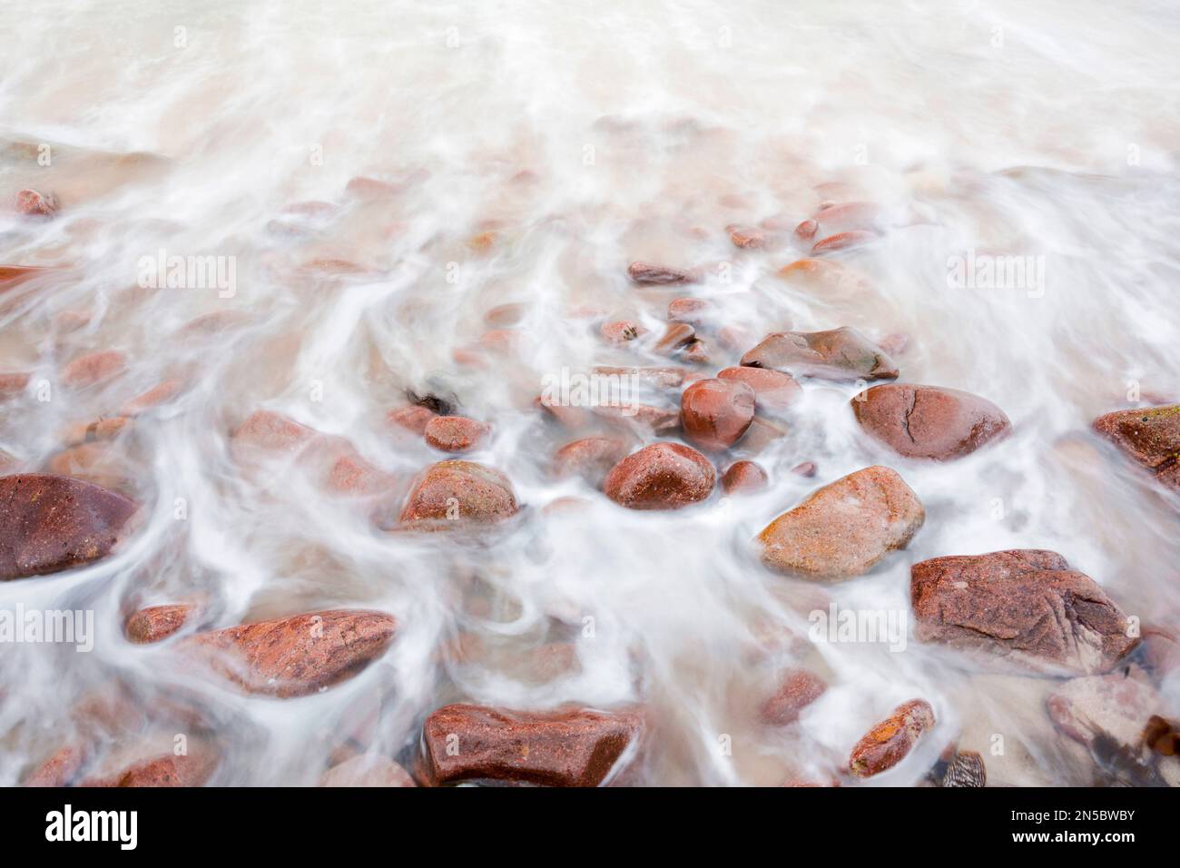 Wellen an einem Strand aus rotem Stein an der Nordwestküste Schottlands, Großbritannien, Schottland Stockfoto