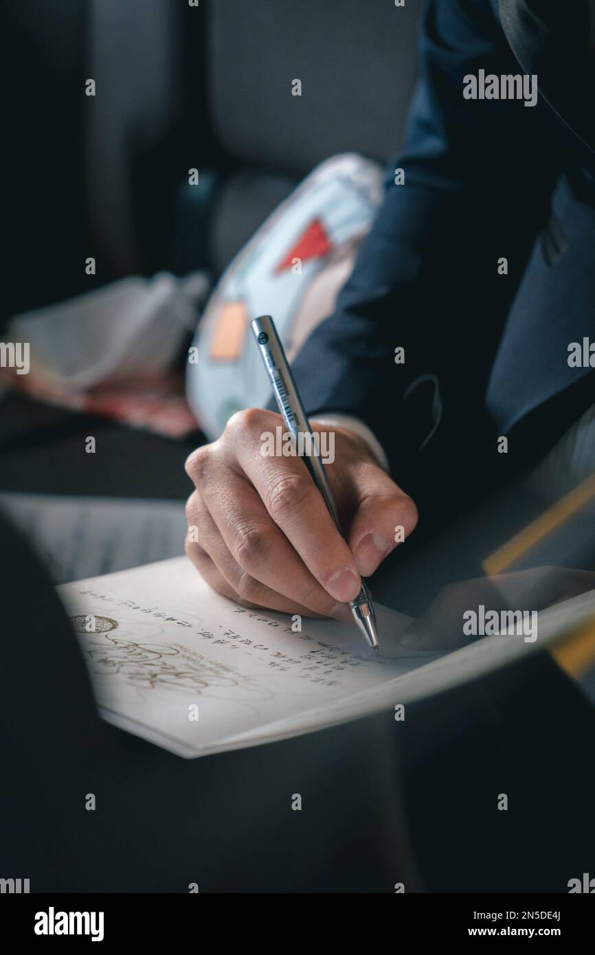 Nahaufnahme der Hand eines erwachsenen Mannes, der einen Brief mit Stift in einem formellen Anzug schreibt. Stockfoto