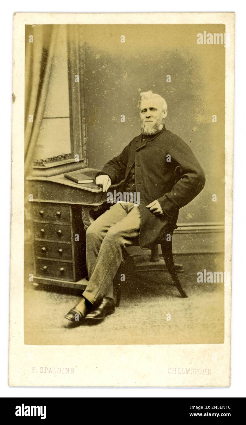 Originaler älterer CDV aus der viktorianischen Zeit (carte de Visite oder Visitenkarte) eines Gentleman, der am Schreibtisch sitzt und einen Sackmantel (für ungezwungene Tageskleidung) aus dem Studio von F Spalding, Tindal Square, Chelmsford, Essex, Großbritannien trägt Fred Spalding Senior gründete 1862 das Familienunternehmen. Gegen Ende der 1860er Jahre Stockfoto