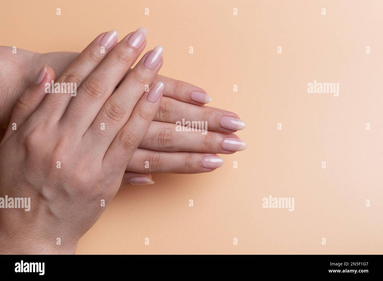 Nahaufnahme von Frauenhänden mit Pediküre auf beigefarbenem Hintergrund Stockfoto