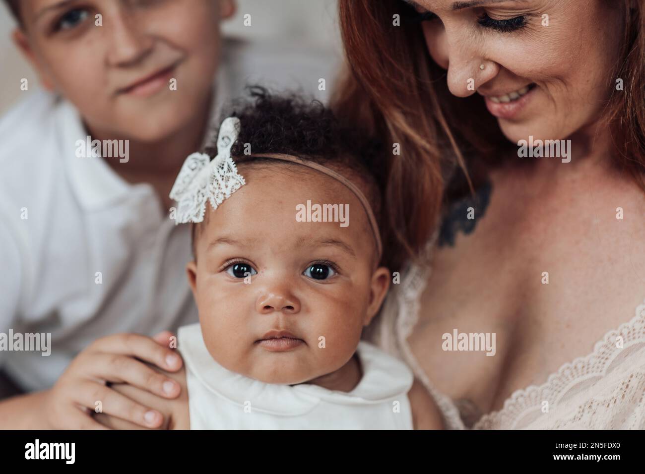 Gemischte Familie mit weißem Sohn und Tochter, die sich in einer gemütlichen Wohnung befindet. Ein afroamerikanischer Mann mit seiner hellhäutigen Frau Ki Stockfoto