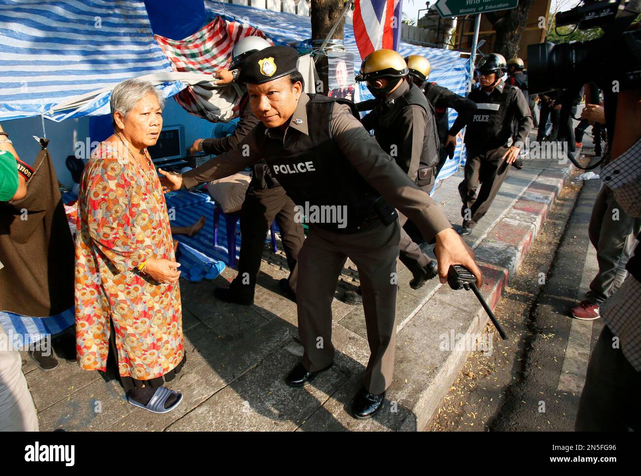 A riot policeman removes a woman from her tent as they retake a stretch of a road occupied by anti-government protesters in Bangkok, Thailand, Friday, Feb. 14, 2014. Riot police cleared the protesters from a major boulevard in the Thai capital in a small victory for authorities Friday as they try to reclaim areas that have been closed during a three-month push to unseat Prime Minister Yingluck Shinawatra. (AP Photo/Wally Santana) Stockfoto