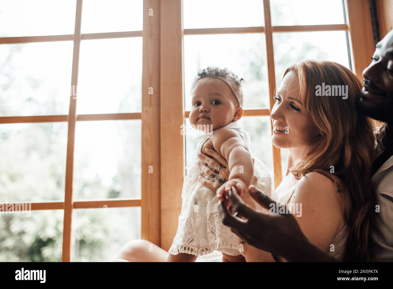 Gemischte Familien mit dunkelhäutigen Kleinkindern verbringen Zeit miteinander. Nutzen Sie das helle Fenster in der gemütlichen Wohnung. Ein afroamerikaner, seine schöne Frau und Stockfoto Gemischte Familien mit dunkelhäutigen Kleinkindern verbringen Zeit miteinander. Nutzen Sie das helle Fenster in der gemütlichen Wohnung. Ein afroamerikaner, seine schöne Frau und Stockfoto
