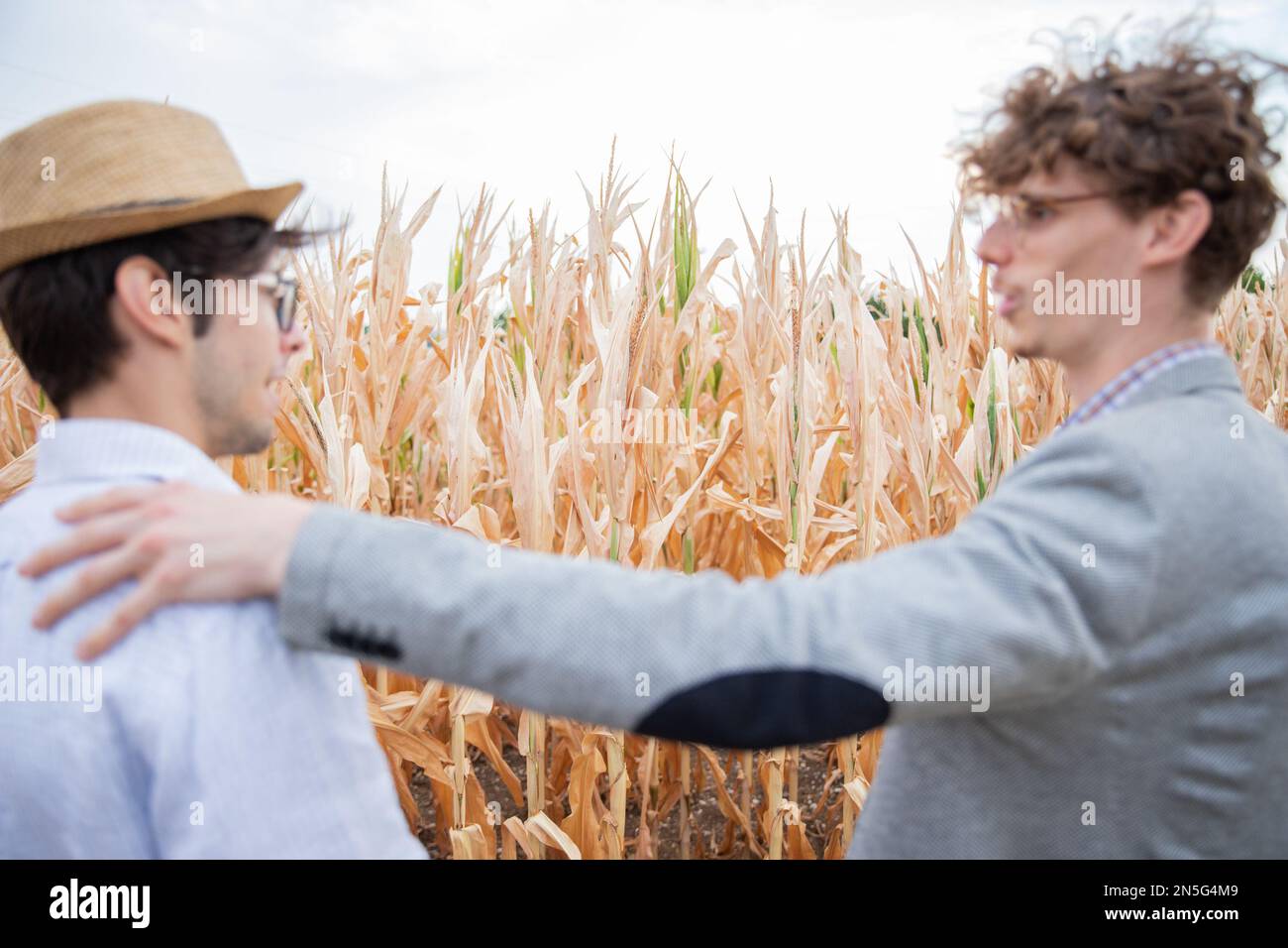 Ein Versicherungsvertreter, der mit einem Farmer auf den Feldern spricht, sich auf die Felder konzentriert, Menschen, die nicht im Fokus sind. Stockfoto