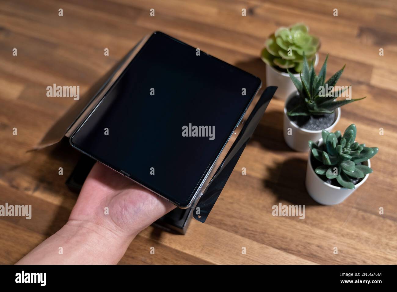 Samsung Galaxy Z Fold 4 in grau-grüner Farbe. Ein Mann packt das neue Handy aus. Stockfoto