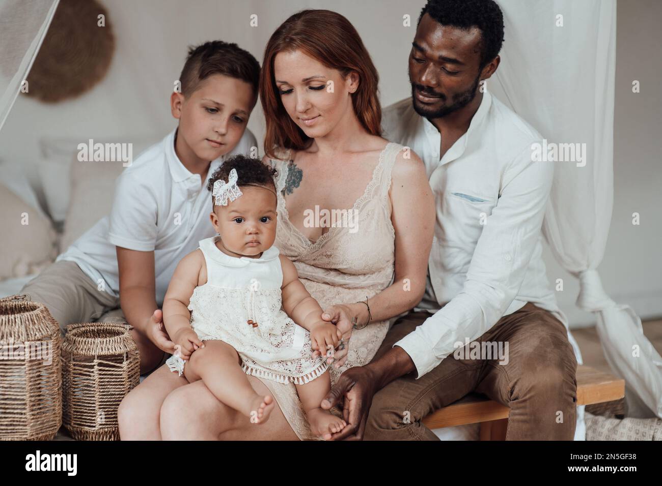 Gemischte Familie mit weißem Sohn und Tochter, die sich in einer gemütlichen Wohnung befindet. Ein afroamerikanischer Mann mit seiner hellhäutigen Frau Ki Stockfoto