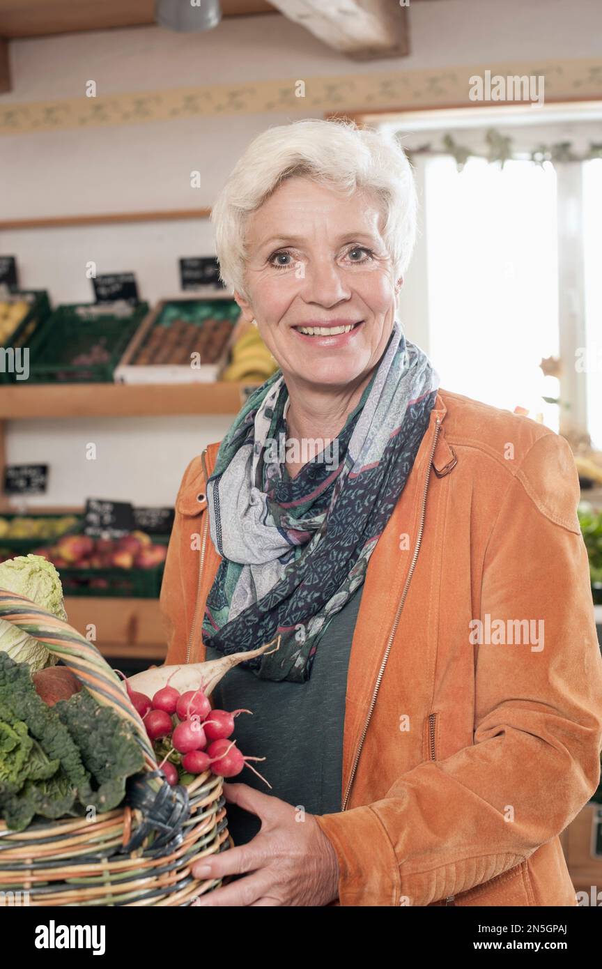 Porträt einer reifen Frau, die Gemüse auf dem Bauernhof kauft und lächelt, Bayern Stockfoto