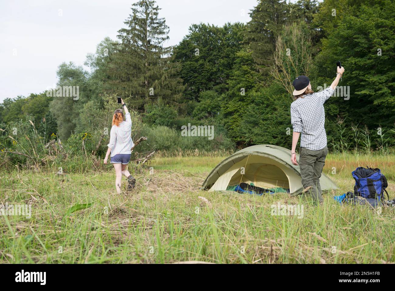 Ein junges Paar, das vor dem Zelt in Bayern Mobilfunk erreichen will Stockfoto