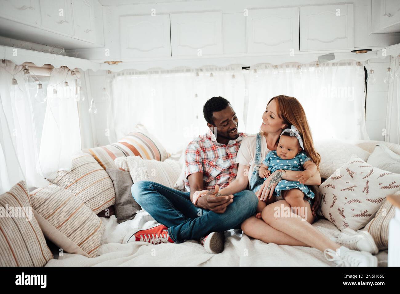 Gemischte, lächelnde Familie und dunkelhäutige kleine Tochter verbringen Zeit zusammen im Trailer. Ein afroamerikaner, seine schöne Frau und sein kleines Kind Stockfoto