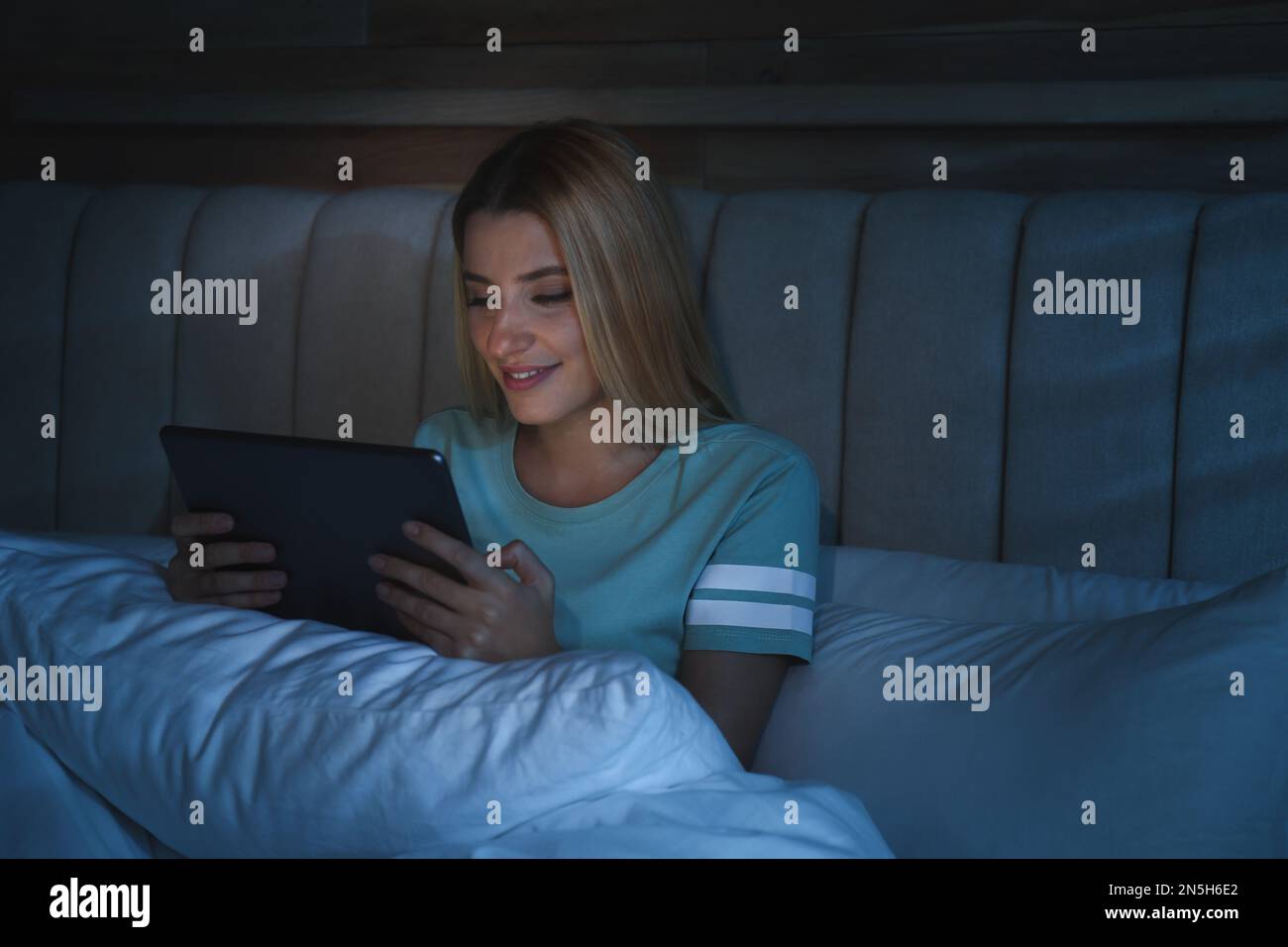 Junge Frau, die nachts ein Tablet im Bett benutzt. Schlafstörungen Stockfoto