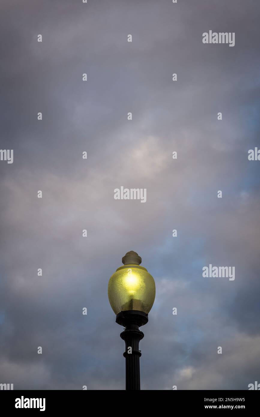 Beleuchtete Straßenlampe vor stimmungsvollem Dämmerlichthimmel Stockfoto