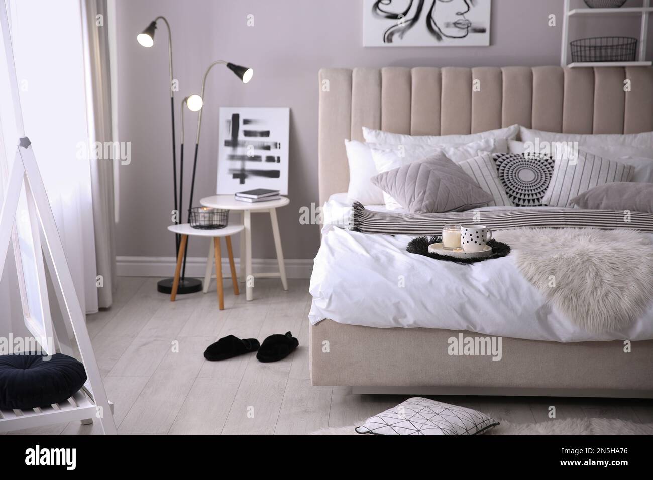 Gemütliche Innenausstattung des Schlafzimmers mit Kissen und gestreifter Decke Stockfoto