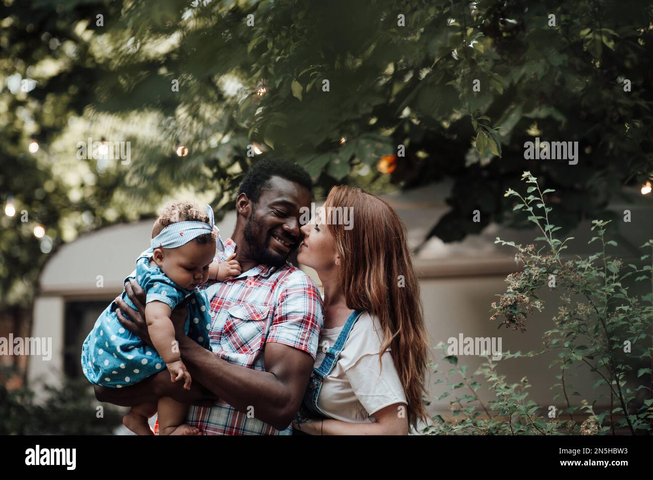 Gemischte Familien mit dunkelhäutigen Kleinkindern verbringen Zeit mit Umarmungen und Küssen im Campingpark. Ein afroamerikaner, seine schöne Frau und li Stockfoto