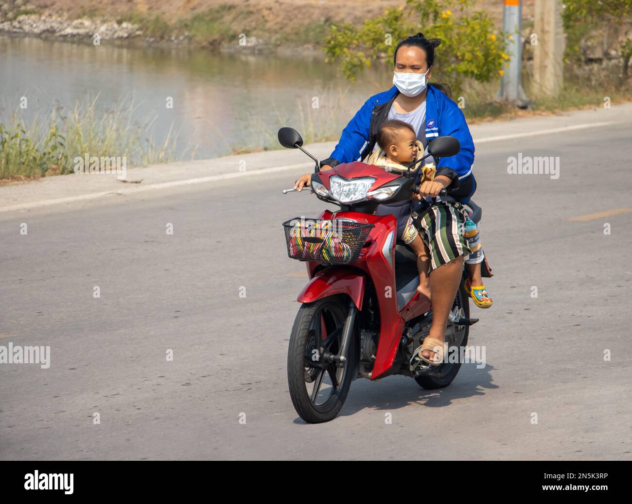 SAMUT PRAKAN, THAILAND, FEBRUAR 01 2023, Eine Frau fährt mit dem Baby auf einem Motorrad. Stockfoto