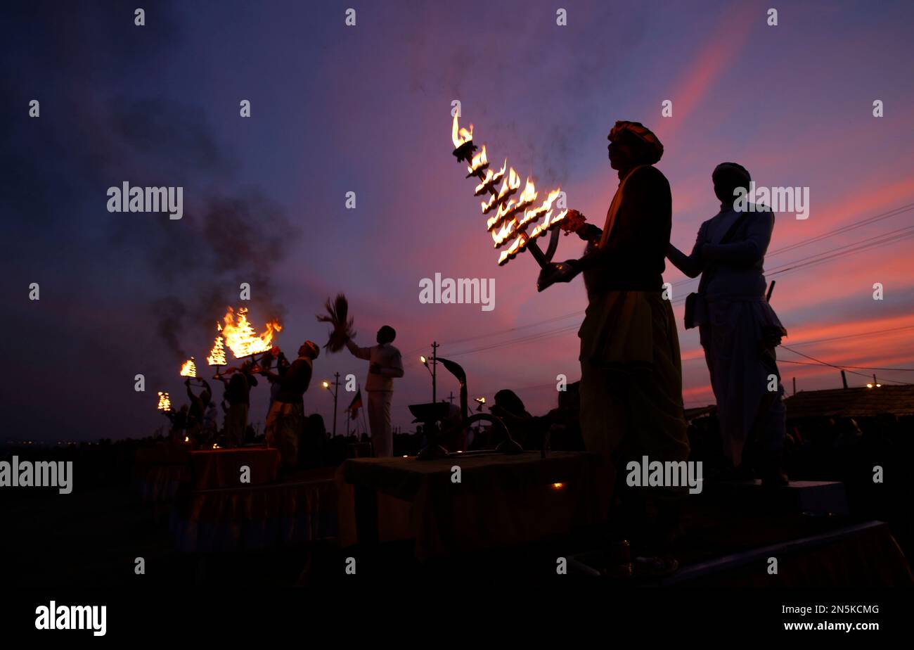 Indian Hindu priests rotate traditional oil lamps as they perform