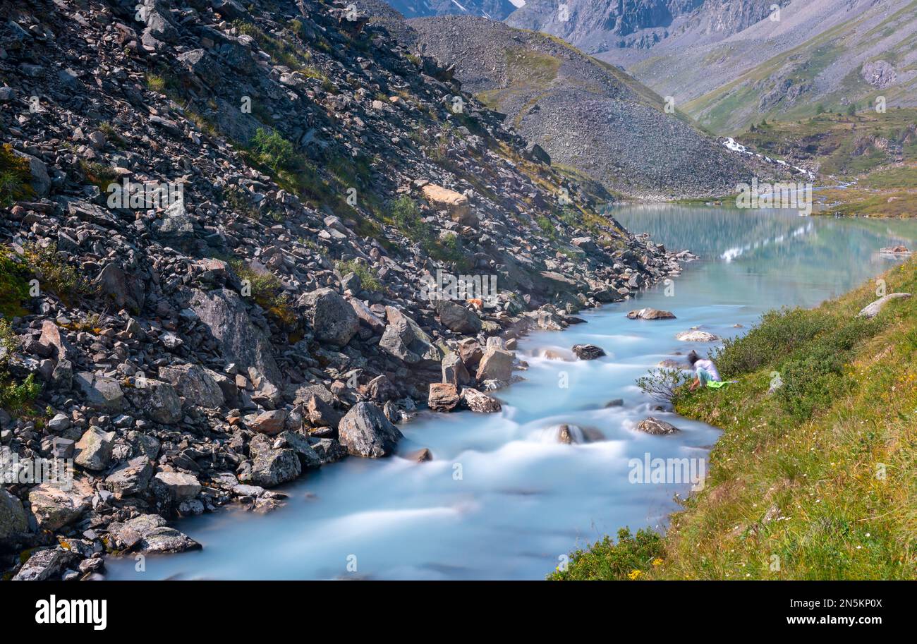 An einem Sommertag fließt ein alpiner Bach über Felsen in der Nähe von Bergen von einem See in Altai, Sibirien. Stockfoto