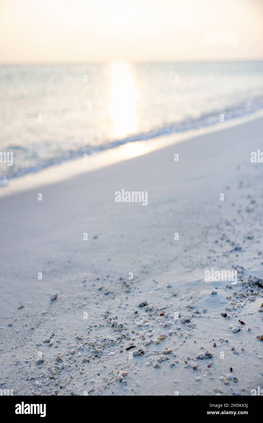 Hintergrund eines leeren Sandstrands am Wasserrand mit Blick auf den Sonnenuntergang im Indischen Ozean; die Malediven in Asien. Konzept - futuristisch Stockfoto