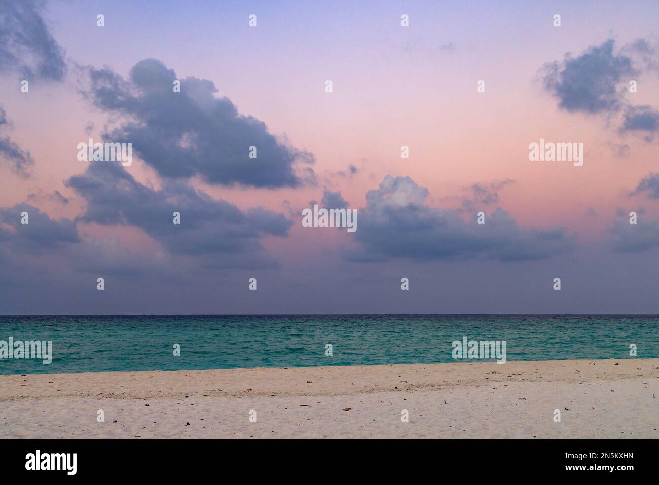 Farbenfrohes Sandmeer und Himmel; Strandlandschaft des Indischen Ozeans kurz nach Sonnenuntergang, die Malediven, Asien. Nützlich als Hintergrund Stockfoto