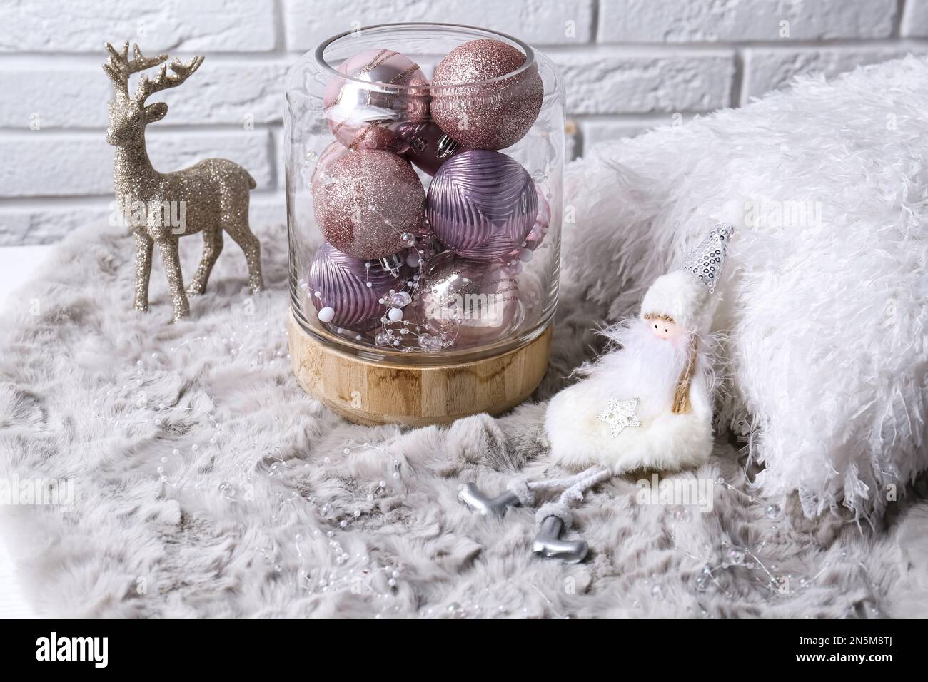 Komposition mit wunderschönen pinkfarbenen Weihnachtskugeln auf grauem Fell Stockfoto