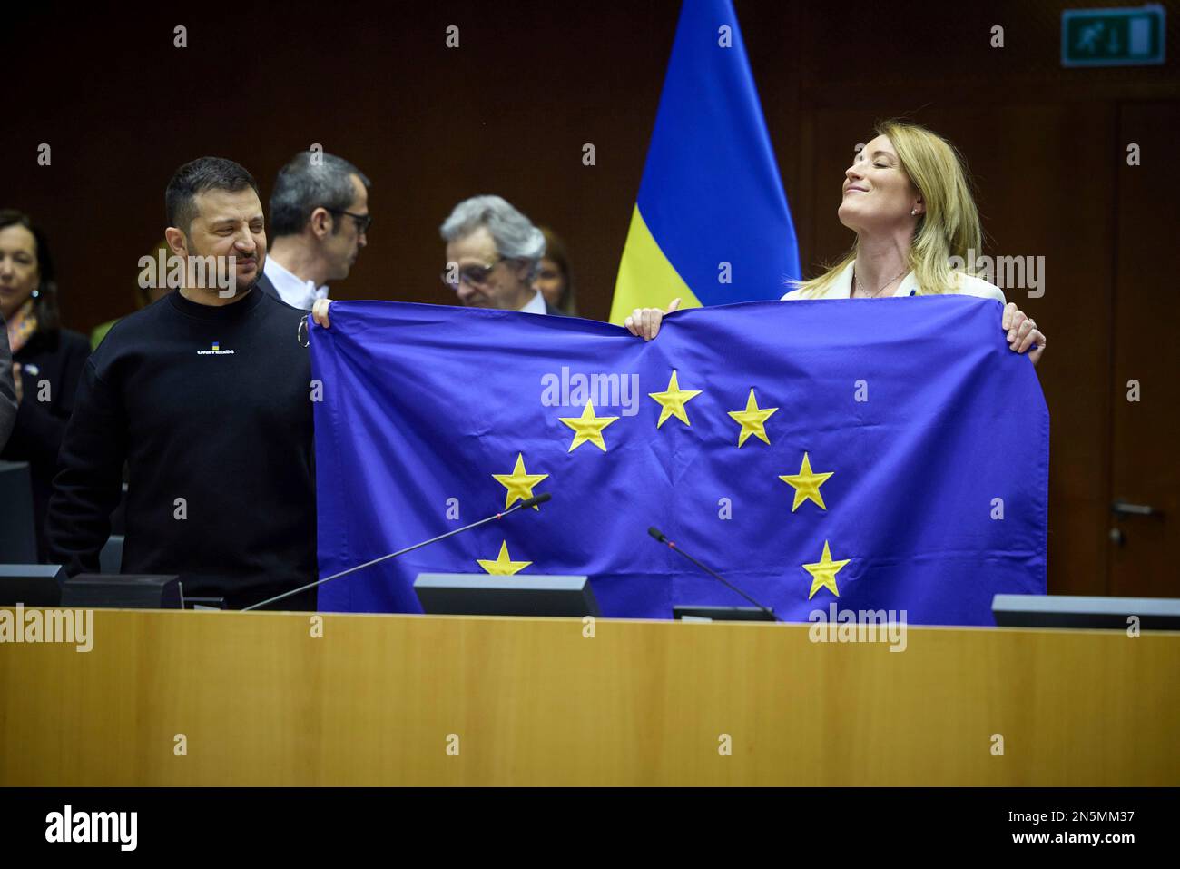 Brüssel, Belgien. 09. Februar 2023. Der ukrainische Präsident Volodymyr Zelenskyy, Linke, hält nach seiner Ansprache auf einer außerordentlichen Plenarsitzung im parlament am 9. Februar 2023 in Brüssel, Belgien, mit der Rechten des Präsidenten des Europäischen Parlaments, Roberta Metsola, eine Flagge der Europäischen Union hoch. Kredit: Pool Photo/Pressestelle Des Ukrainischen Präsidenten/Alamy Live News Stockfoto