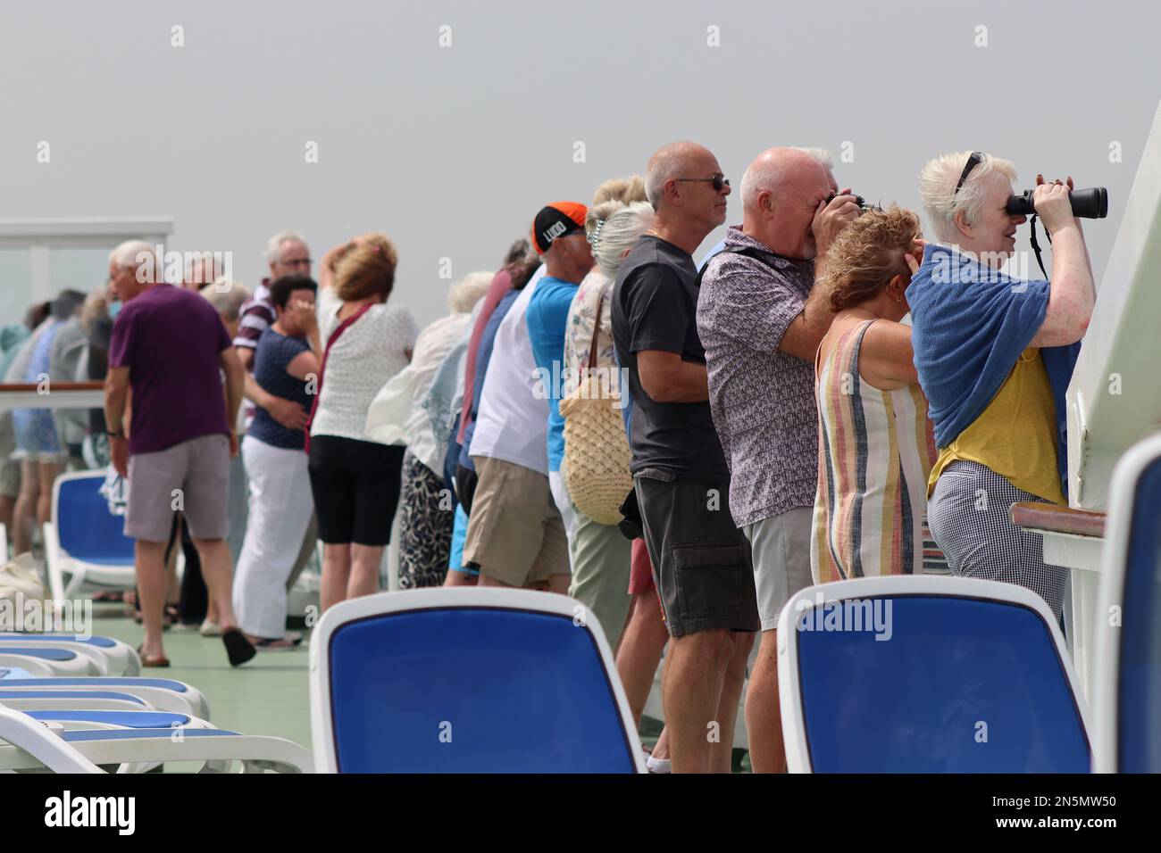 Kreuzfahrtgäste sehen auf dem Sonnendeck der Aurora die erfolgreiche Überführung von Migranten auf das algerische Marineschiff Al-Munjid. Stockfoto