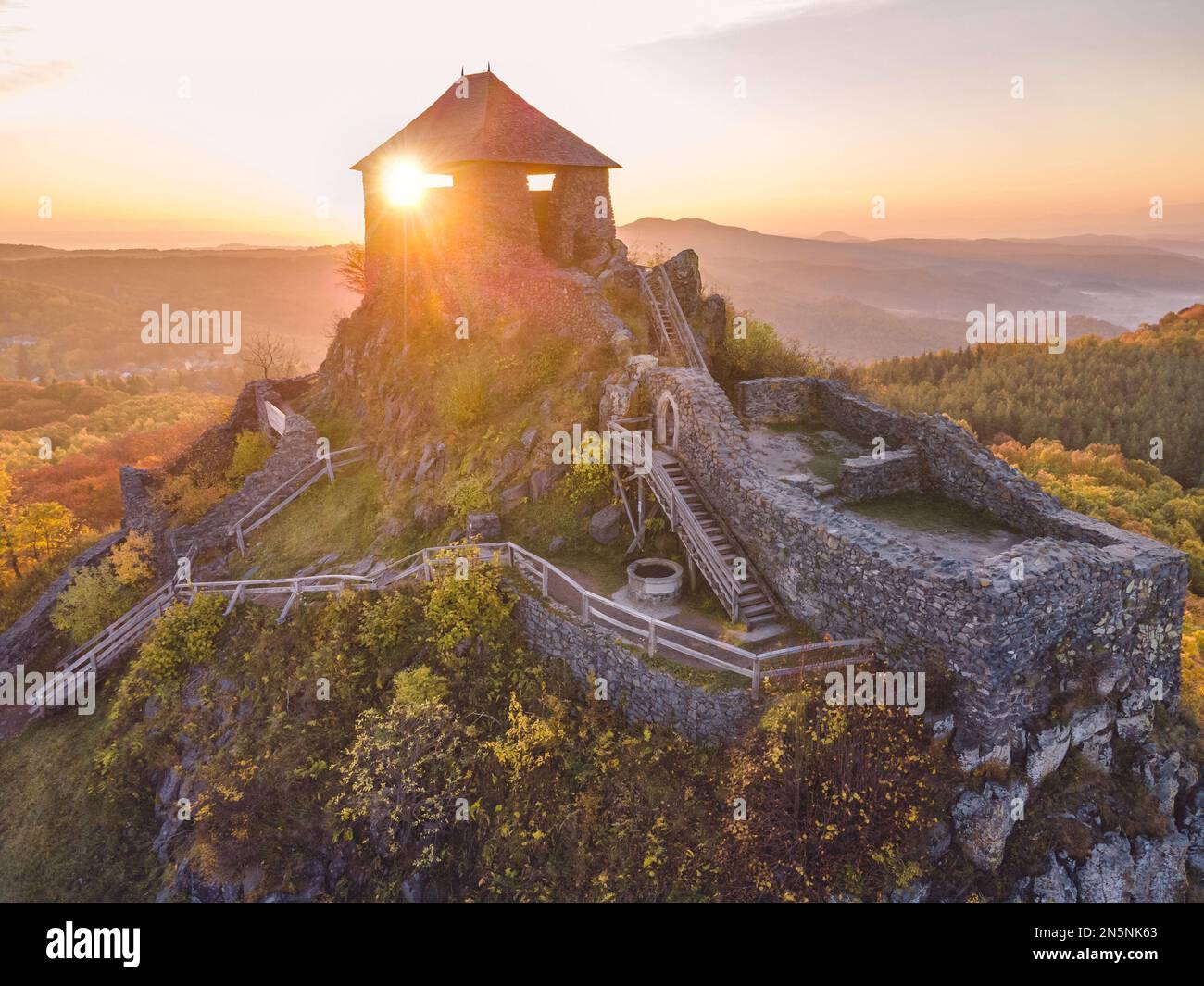 Die Burg Salgó, die sich an einem Herbstmorgen mit den Lichtern des Sonnenaufgangs auf dem 625 Meter hohen Vulkangipfel des Medves-Plateaus befindet, aus der Vogelperspektive aus der Vogelperspektive aus der Vogelperspektive Stockfoto