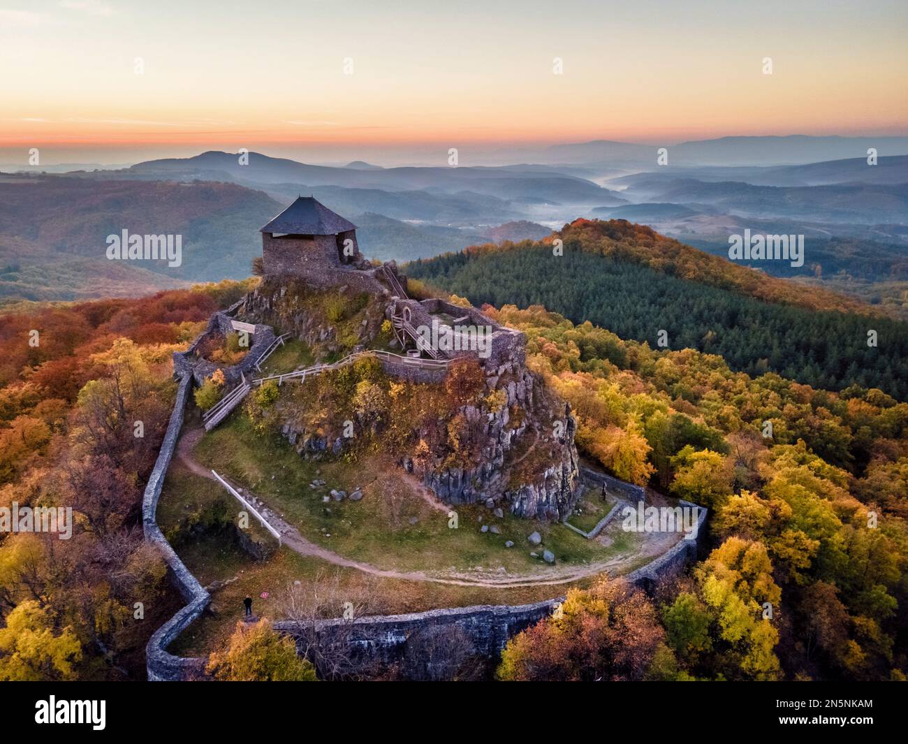 Die Burg Salgó, die sich an einem Herbstmorgen mit den Lichtern des Sonnenaufgangs auf dem 625 Meter hohen Vulkangipfel des Medves-Plateaus befindet, aus der Vogelperspektive aus der Vogelperspektive aus der Vogelperspektive Stockfoto