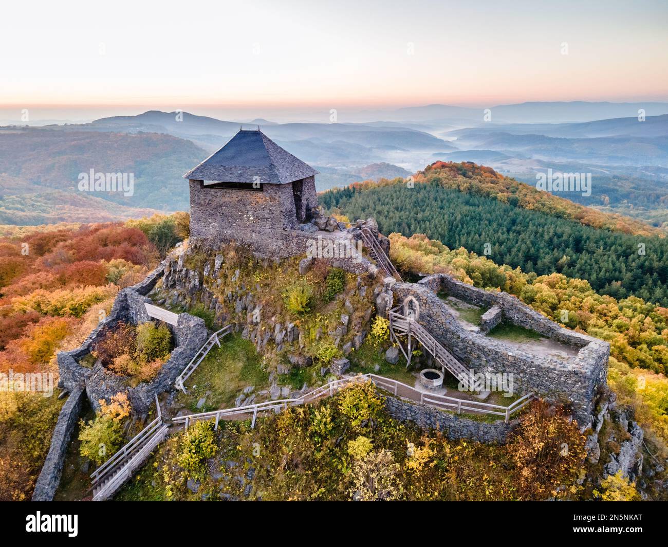 Die Burg Salgó, die sich an einem Herbstmorgen mit den Lichtern des Sonnenaufgangs auf dem 625 Meter hohen Vulkangipfel des Medves-Plateaus befindet, aus der Vogelperspektive aus der Vogelperspektive aus der Vogelperspektive Stockfoto