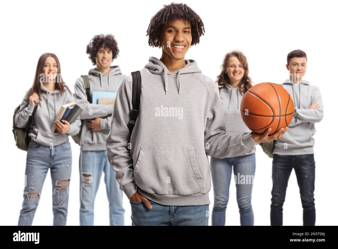 afroamerikanischer Schüler mit einem Basketball und andere Schüler im Rücken isoliert auf weißem Hintergrund Stockfoto